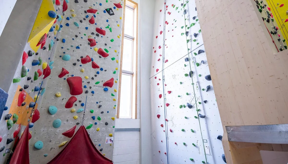Innenansicht einer modernen Kletterhalle mit bunten Kletterwänden und verschiedenen Routen, mit Selbstischerungsanlage. | © DAV Konstanz, Michael Dörfer
